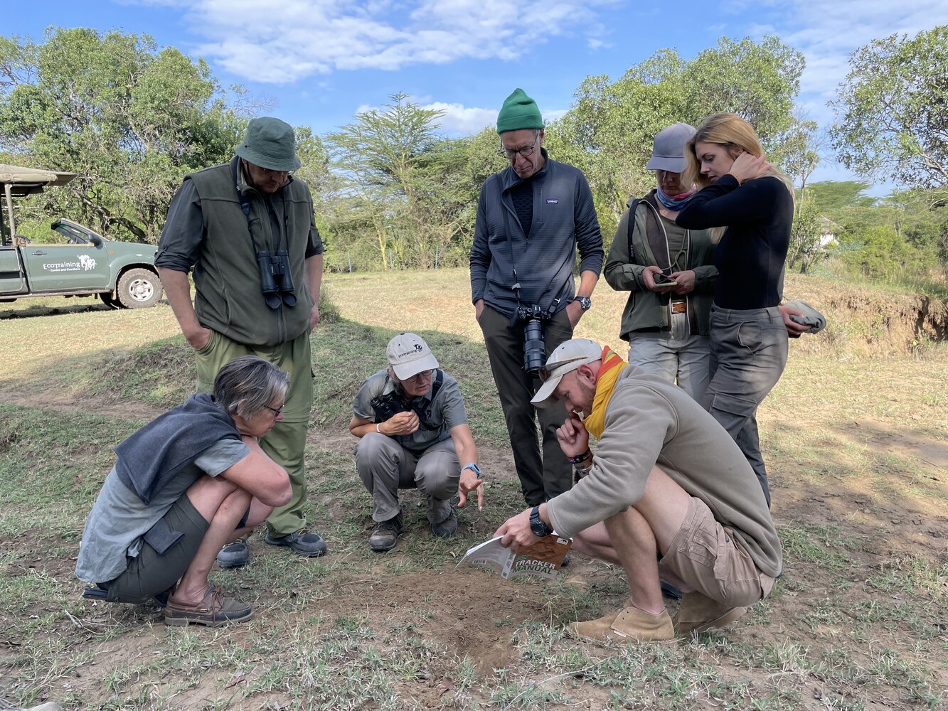 Several people examining animal tracks together in the sand